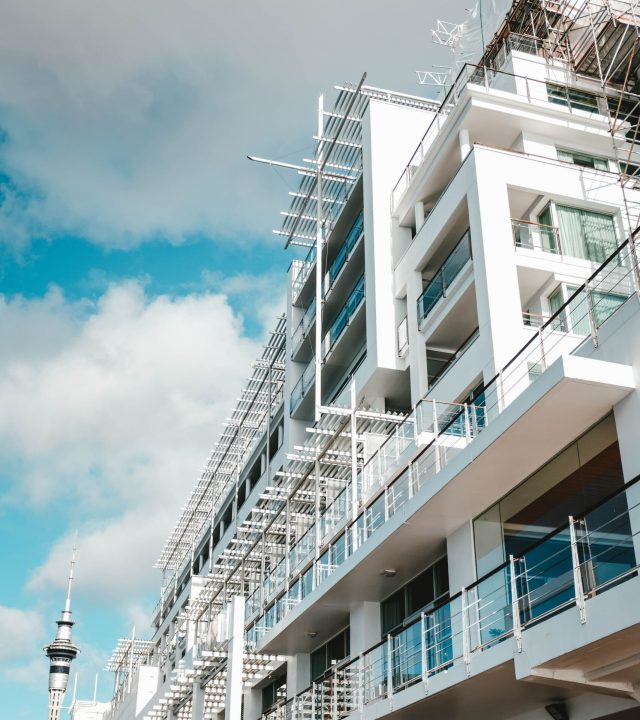 A vertical low angle shot of a white modern building touching the cloudy sky